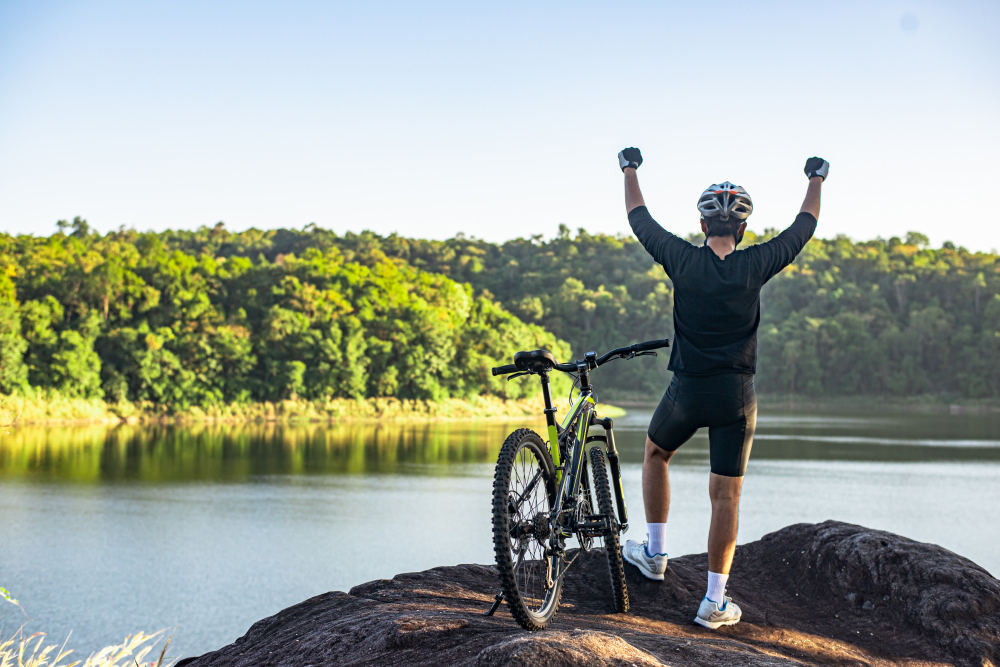 Mountain bike cyclist standing on top of a mountain with bicycle